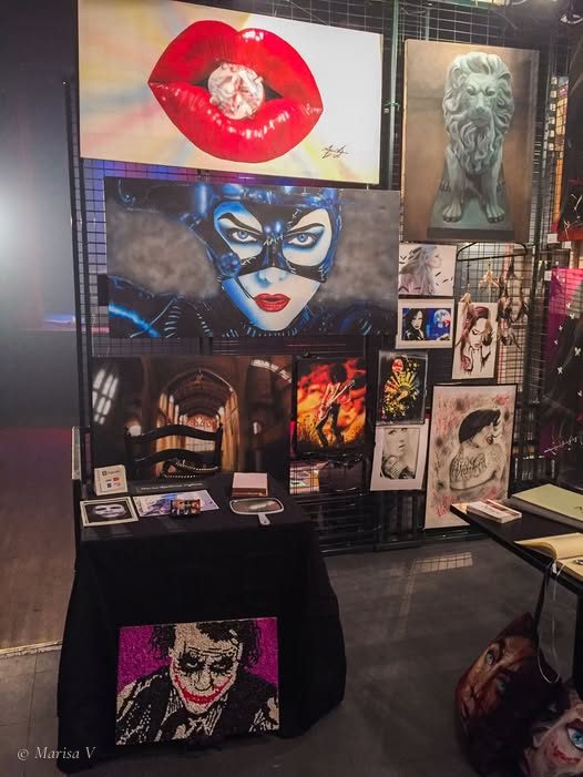 Son kiosque à RAW Artists, en 2015 : des lèvres rouges qui mordent un diamant, un portrait masqué en bleu, un lion de pierre et des dessins encadrés.