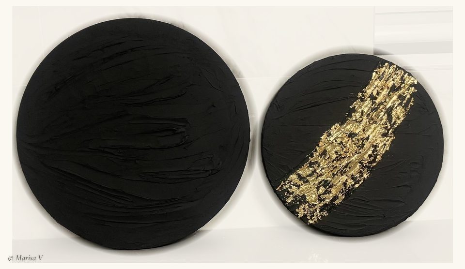 Two round, textured black canvases side by side; the smaller one is crossed by a band of gold leaf.