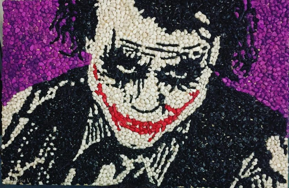 Pebble mosaic of the Joker in black and white with a red grin, on a purple ground.