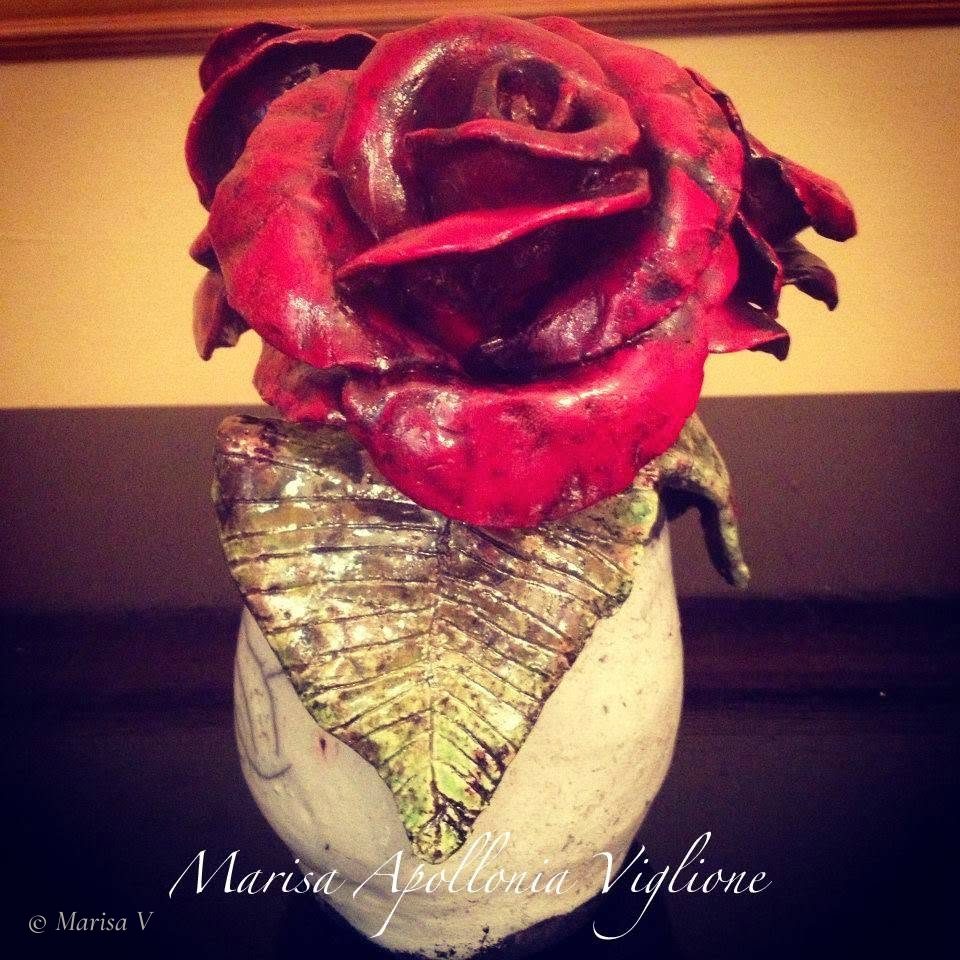 Raku ceramic sculpture: a large red rose and a metallic green leaf on a small crackled white vase.