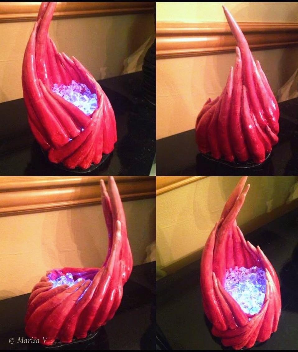 Glossy red flame-shaped ceramic lamp with crystals lit blue-violet at its base.
